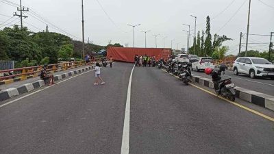 Sebuah truk kontainer berukuran 40 feet terguling di Jembatan Layang Trosobo, Kecamatan Taman, Minggu (29/12/2025) pagi