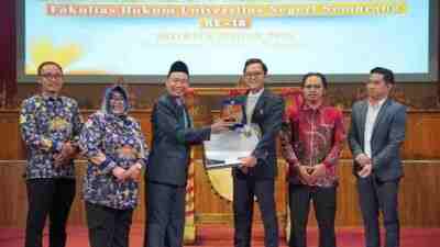 Dekan Fakultas Hukum Unnes Ali Masyhar Menyerahkan Penghargaan kepada Alumni Advokat Ady Putra Cesario